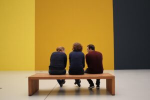Three people sitting in a museum or gallery